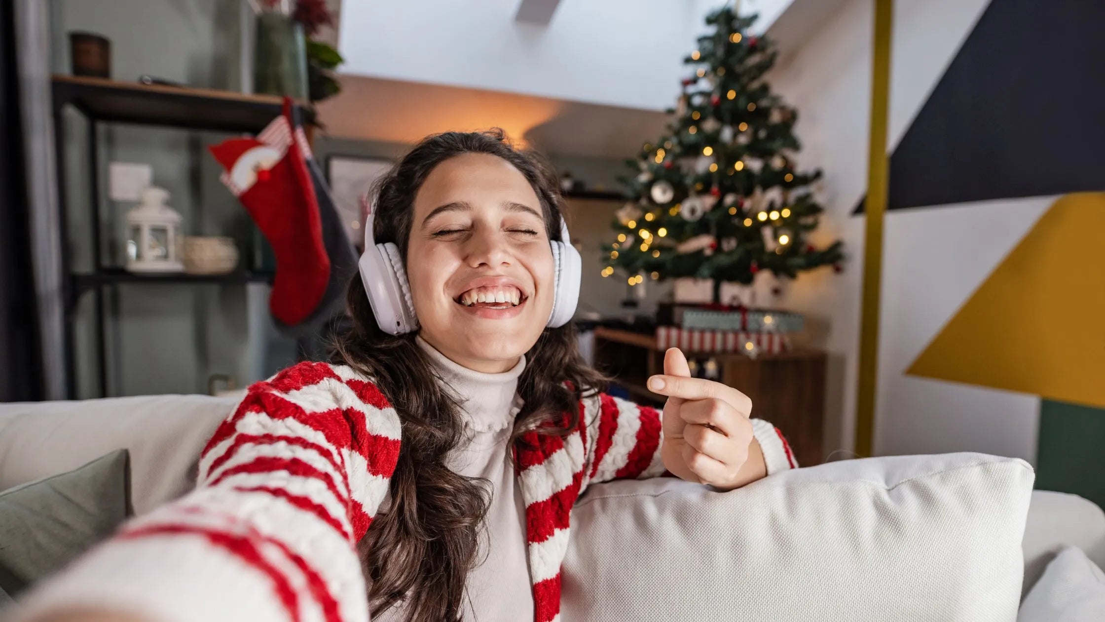 A group of friends enjoying a virtual Secret Santa gift exchange over a video call, with festive decorations in the backgrou